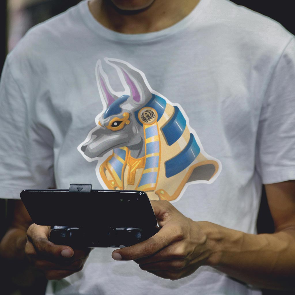 Présentation des t-shirt Noble Daron. Marque créée par Julien Girardet Monsieurju, illustrateur graphiste à Poitiers Un homme joue avec son smartphone et porte un tshirt avec la tête d'Anubis.